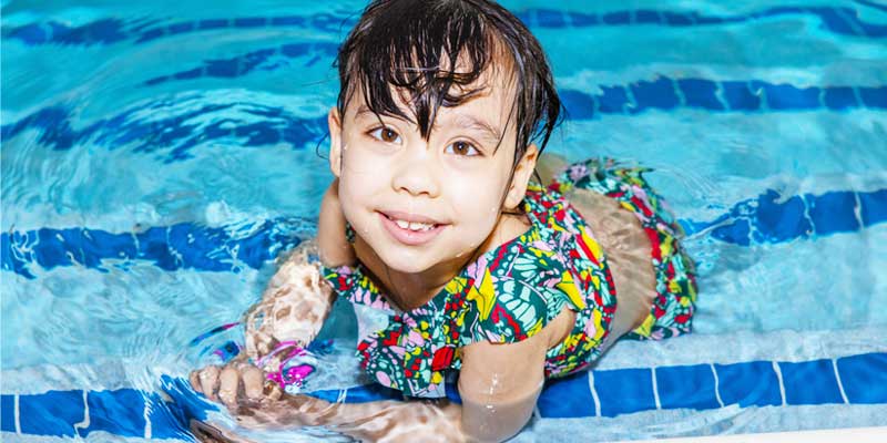 swim-safety, child sitting on steps of swimming pool