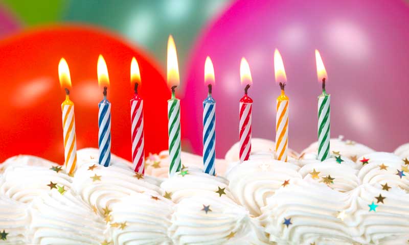 Eight lit, striped candles on a decorated birthday cake at swim birthday party