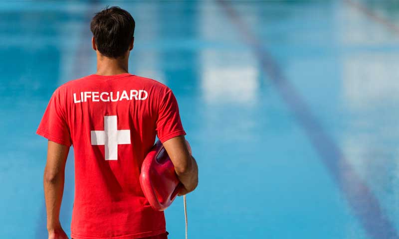 A male lifeguard watching over a large pool