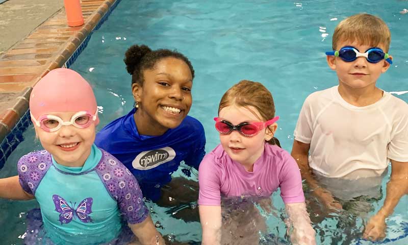 Njswim teacher and her three young students during a swim lesson