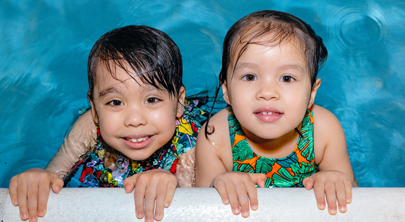 Two young kids swimming in a pool